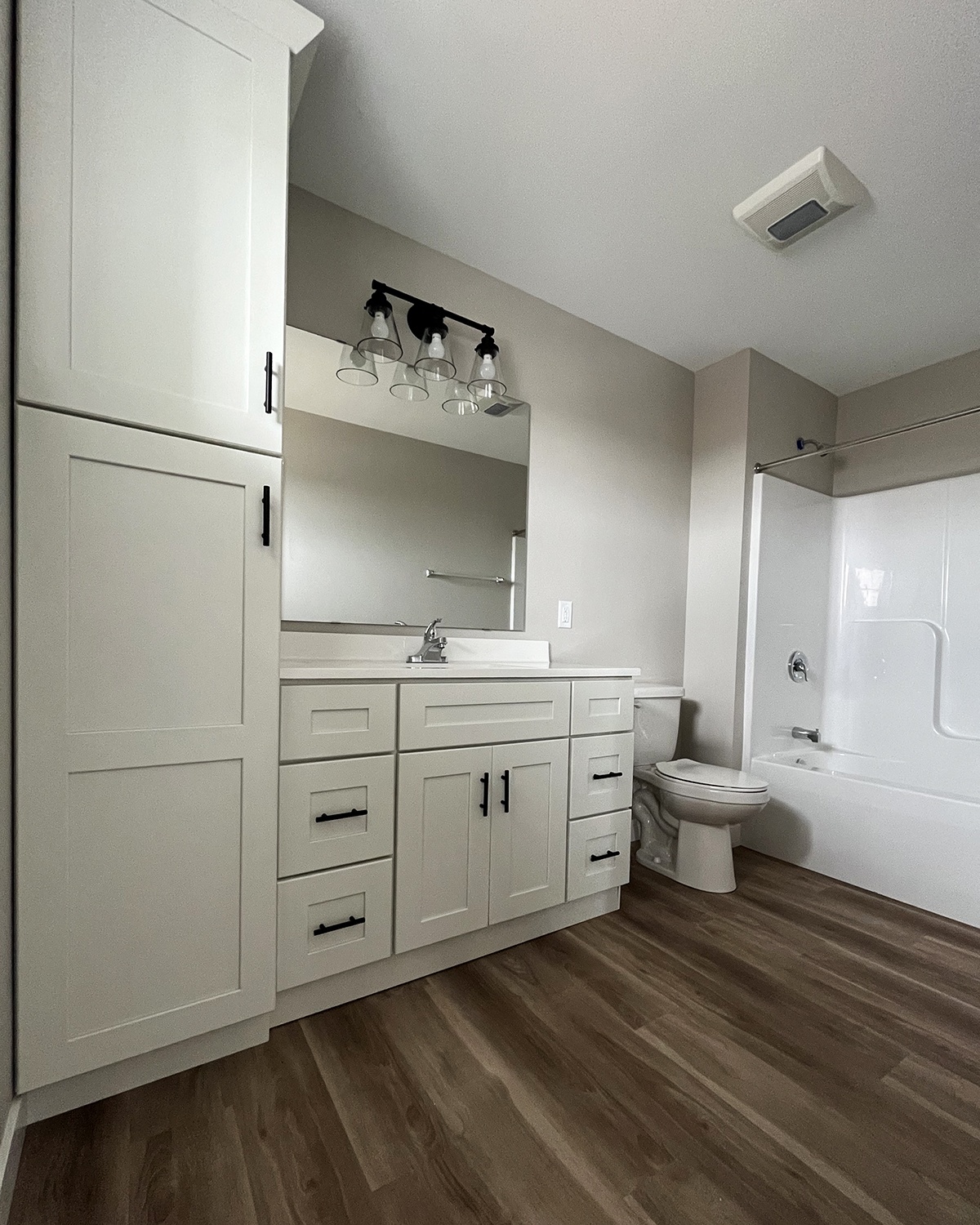 a bathroom with white cabinets and a wooden floor